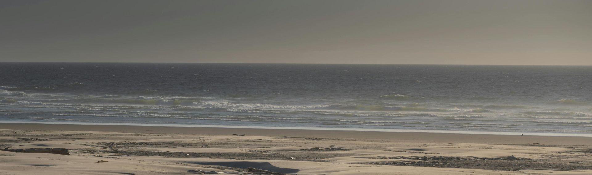 A man runs alone on a deserted beach with a ball, under a clear sky. Perfect for themes of solitude and freedom.
